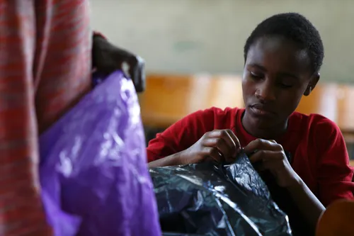 Kenyan youth weaving a basket